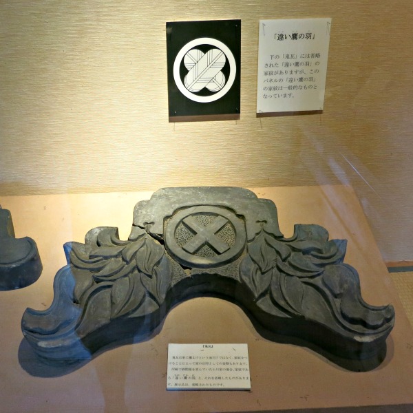 A carved roof finial on display in a museum in japan.  Not how its bottom surface is shaped to fit the tiles.