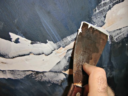 Smoothing the caulk during the plaster ceiling repair requires a wet putty knife