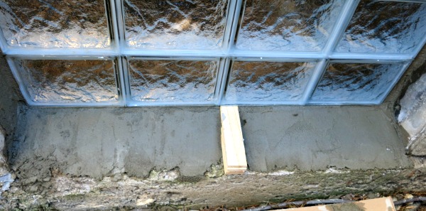 The glass block window is inserted on top of a layer of mortar