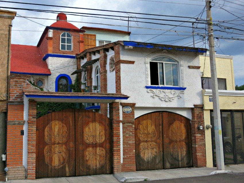 Here the courtyard has gates that match the garage doors. What a great house - Mexican homes are often artfully decorated on the exterior.